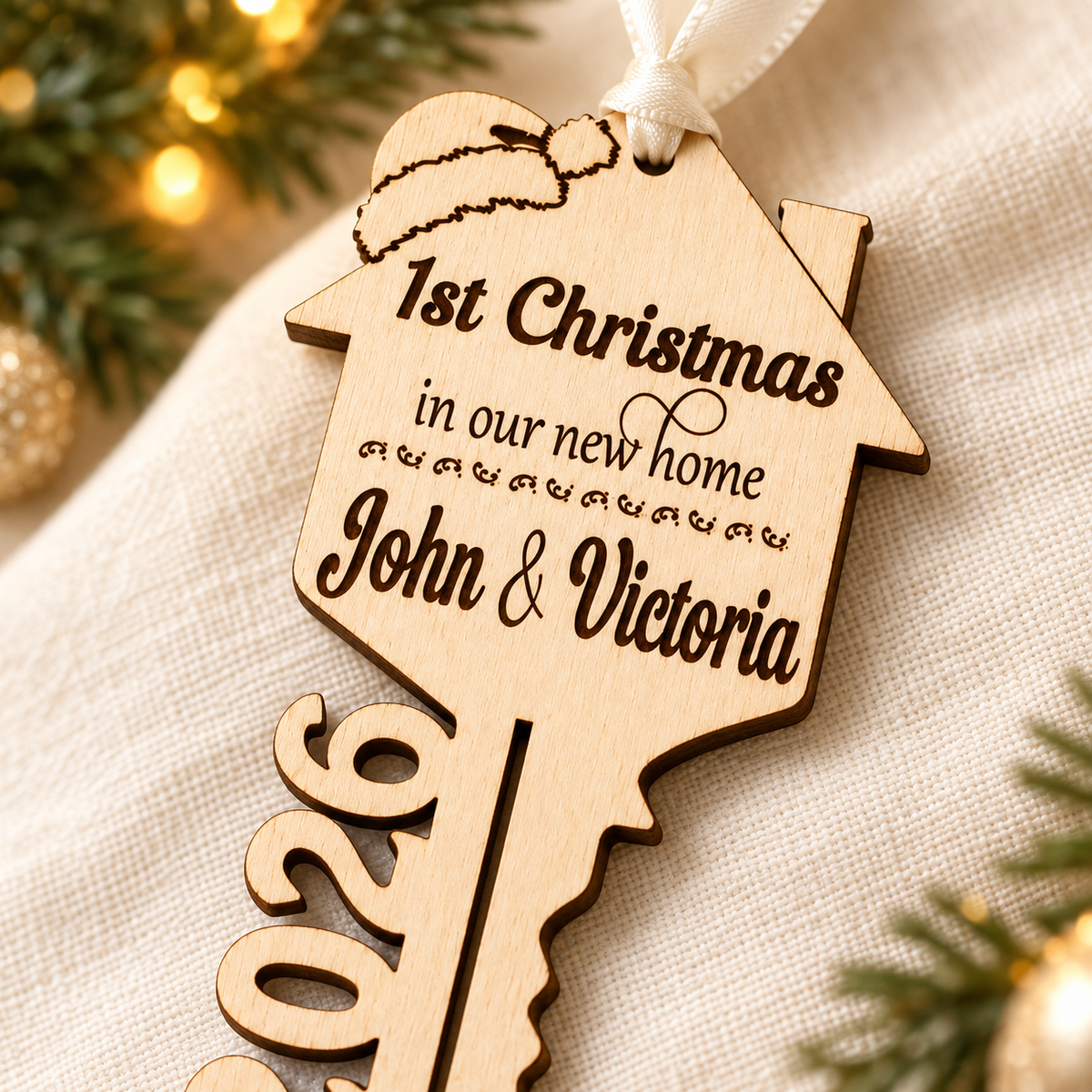 Close-up of natural birch wood grain, laser engraving and Santa hat detail on a personalised new home Christmas bauble