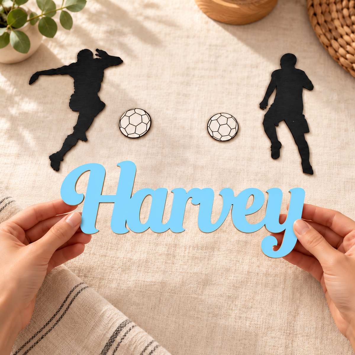 Pastel Blue Harvey connected wooden name held in hands, with the two black players and two white footballs from the set.