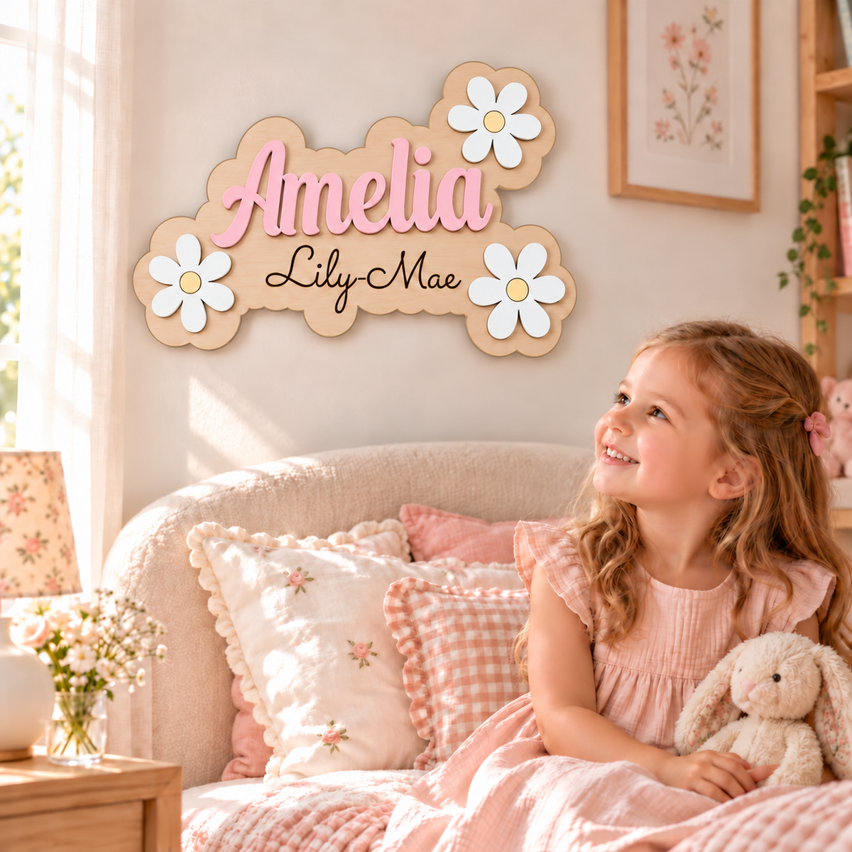 Personalised Amelia wooden name sign with black Lily-Mae engraving, pastel pink lettering and white daisies, displayed in a girl's bedroom.