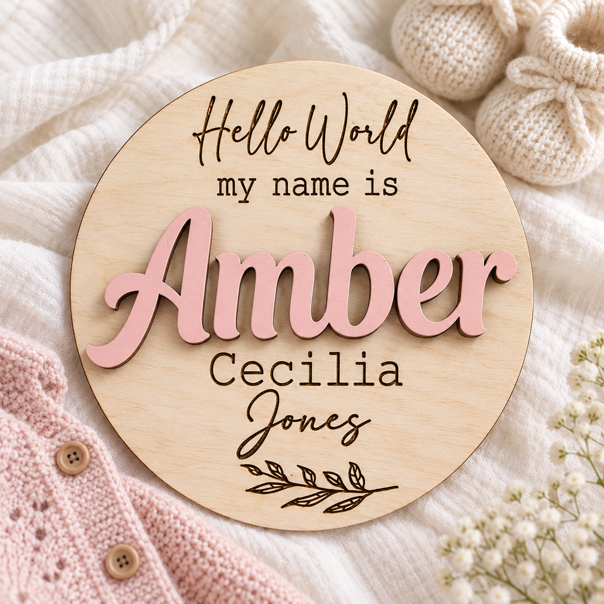 Round wooden baby name disc with Amber in Pastel Pink 3D lettering and Cecilia Jones engraved beneath.