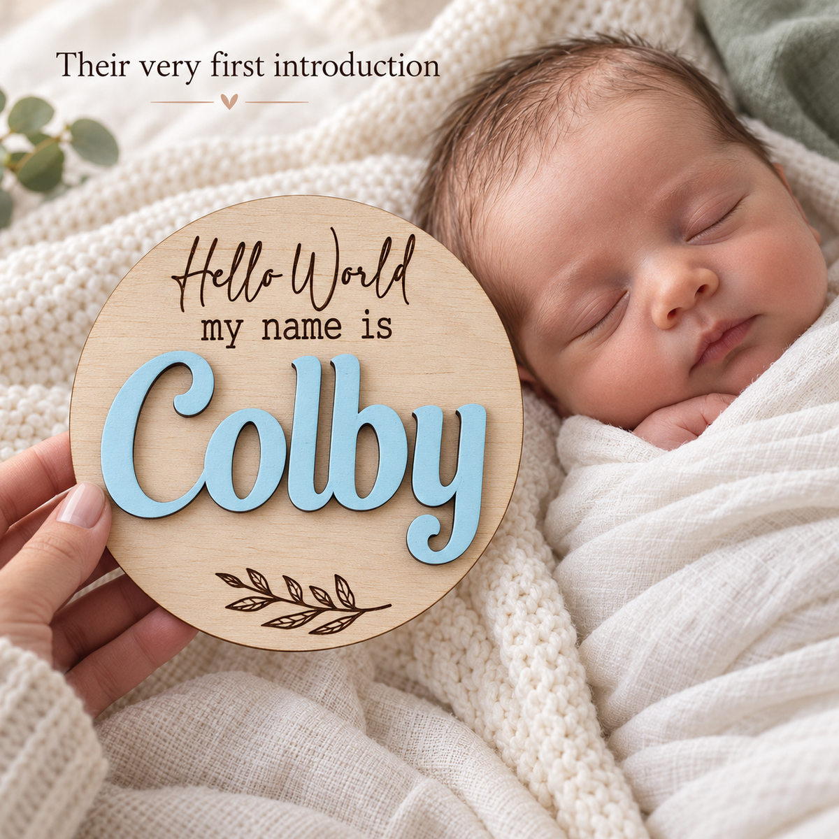 Personalised Colby baby name disc held beside a sleeping newborn for a first name reveal photograph.