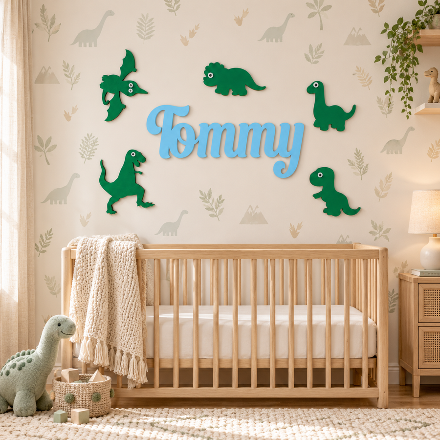 Pastel blue Tommy wooden name with five green dinosaur wall decorations above a natural wood cot in a dinosaur nursery