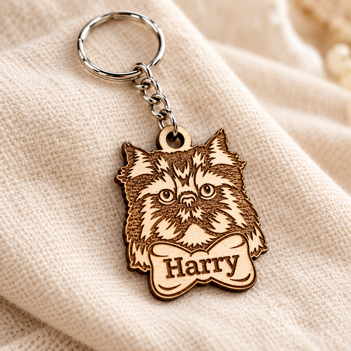 Close-up of Harry engraved on the bottom bow of a natural wooden Persian cat keyring