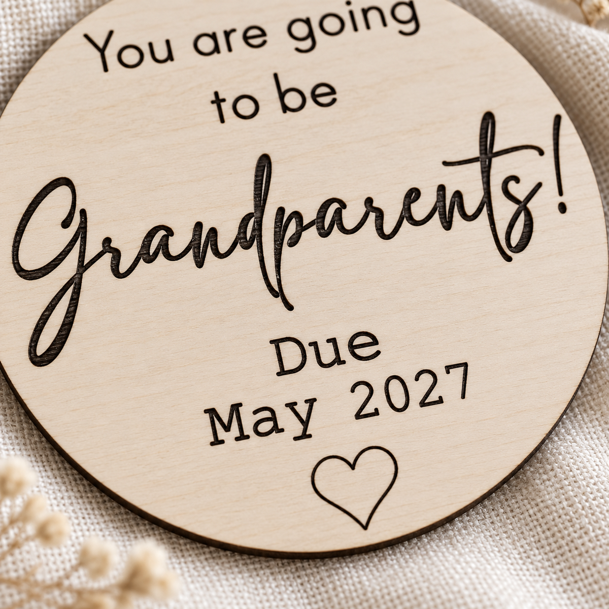 Close-up of black laser engraving, natural wood grain and personalised due date on the grandparents announcement plaque