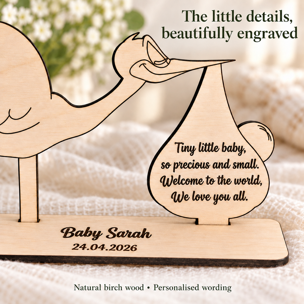 Close-up of dark engraved lettering and natural birch wood on a personalised stork keepsake
