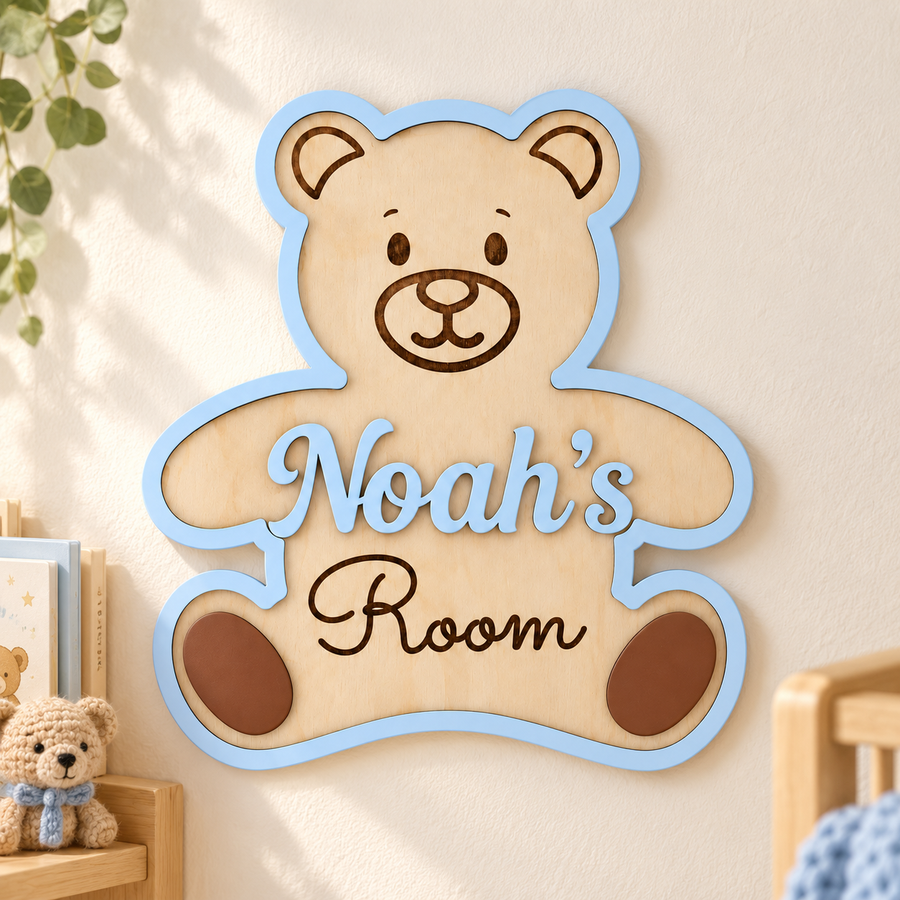 Pastel blue personalised teddy bear name sign with raised Noah’s lettering and engraved Room, displayed on a nursery wall.