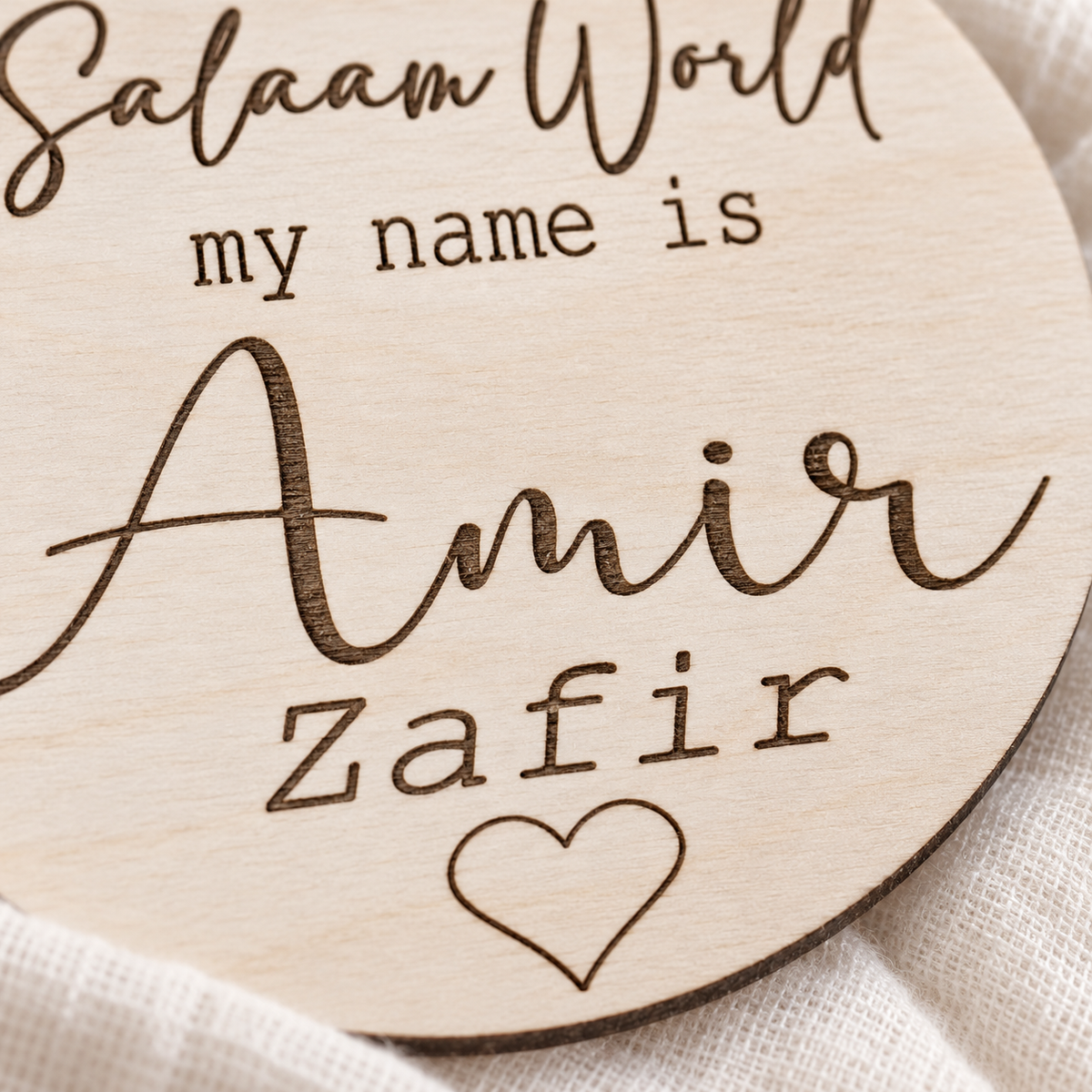 Close-up of dark laser engraved script names and heart detail in natural birch plywood