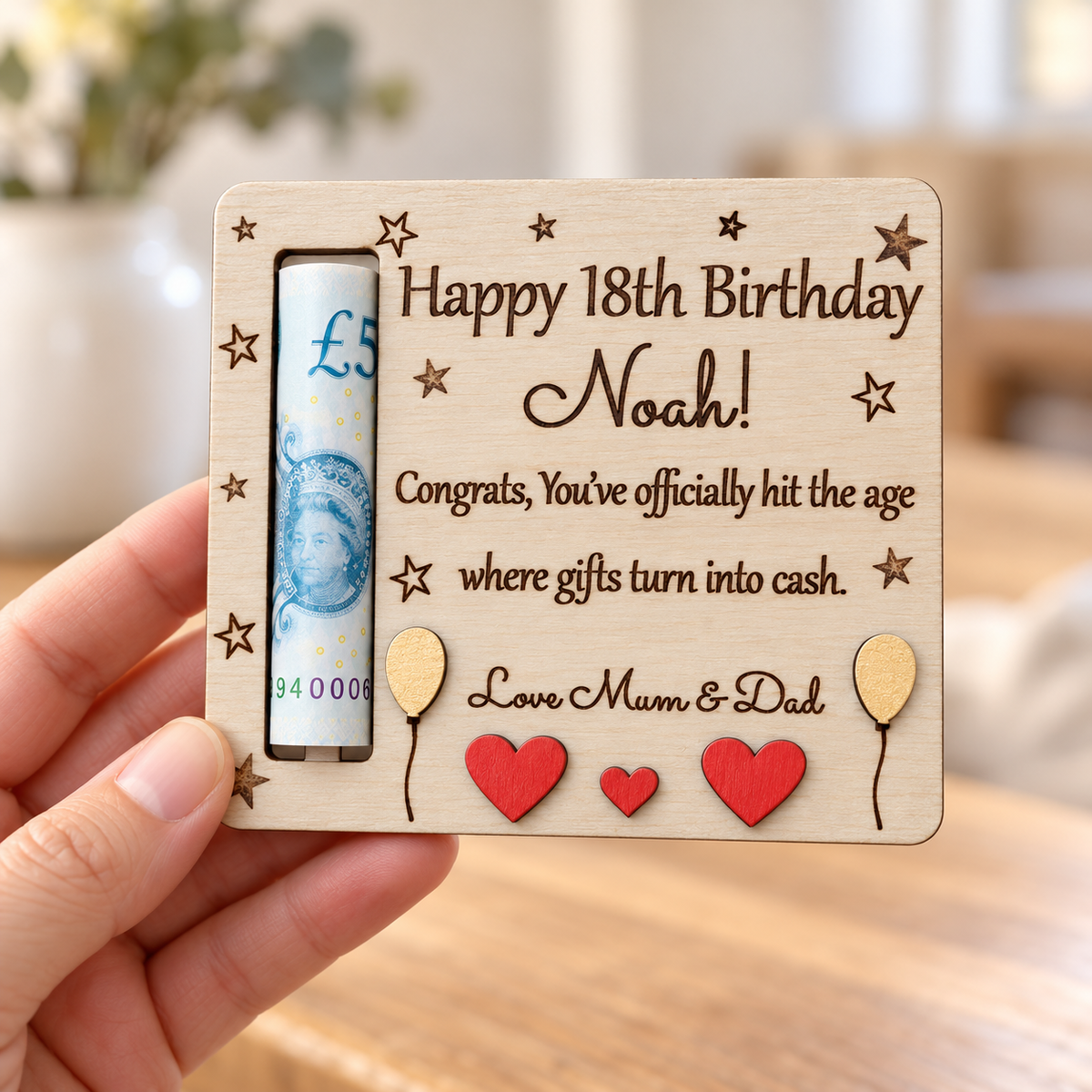 Hand holding a small wooden money holder for Noah's 18th birthday to show the size, engraved message and rolled banknote slot