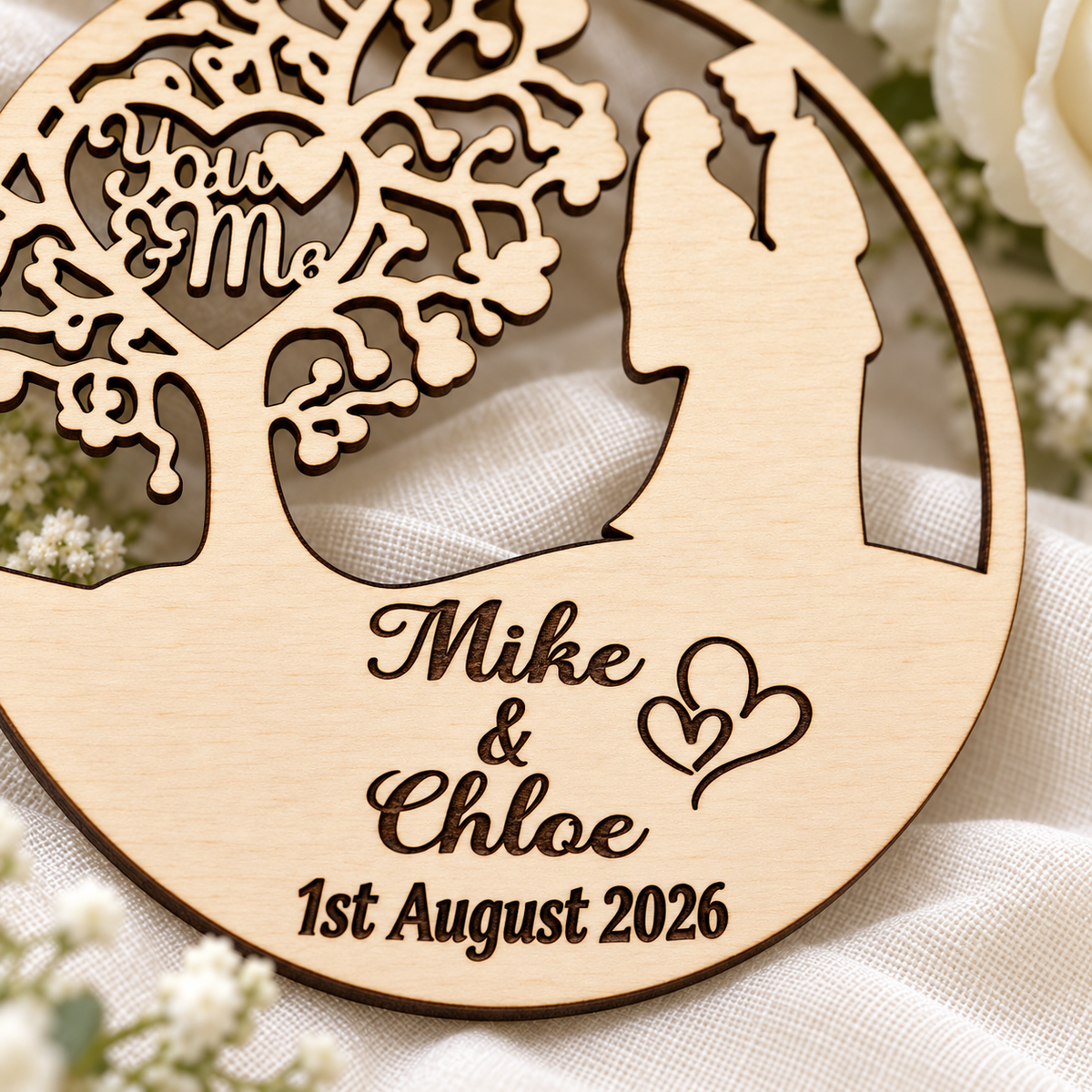 Close-up of crisp dark laser engraving, personalised names, date and double-heart detail on the natural birch wedding ornament.