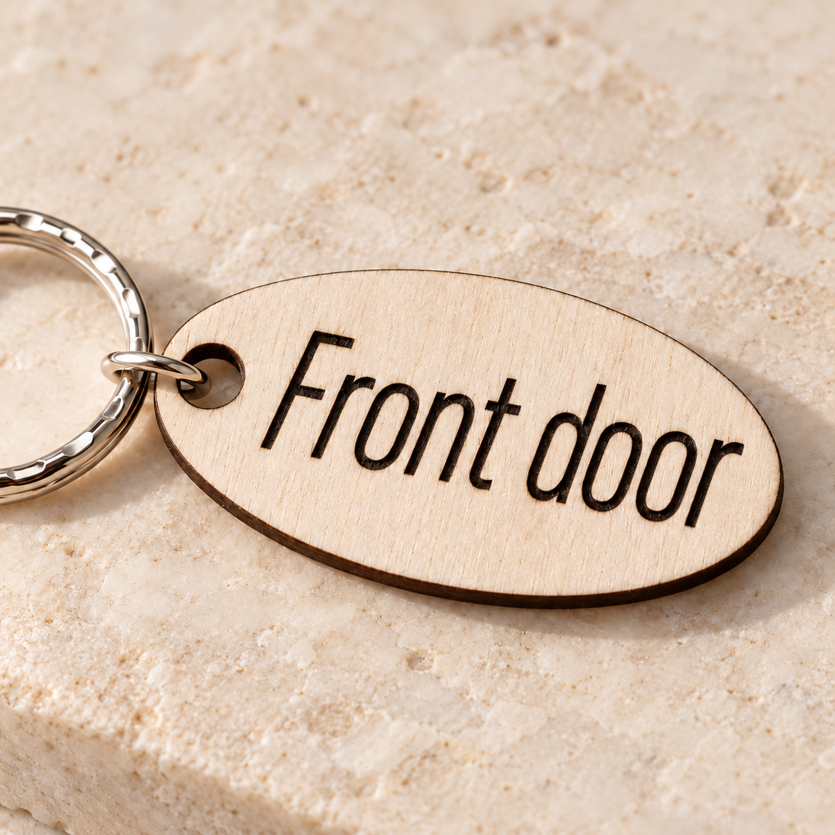 Close-up of dark laser engraving and natural birch plywood grain on a personalised wooden keyring.