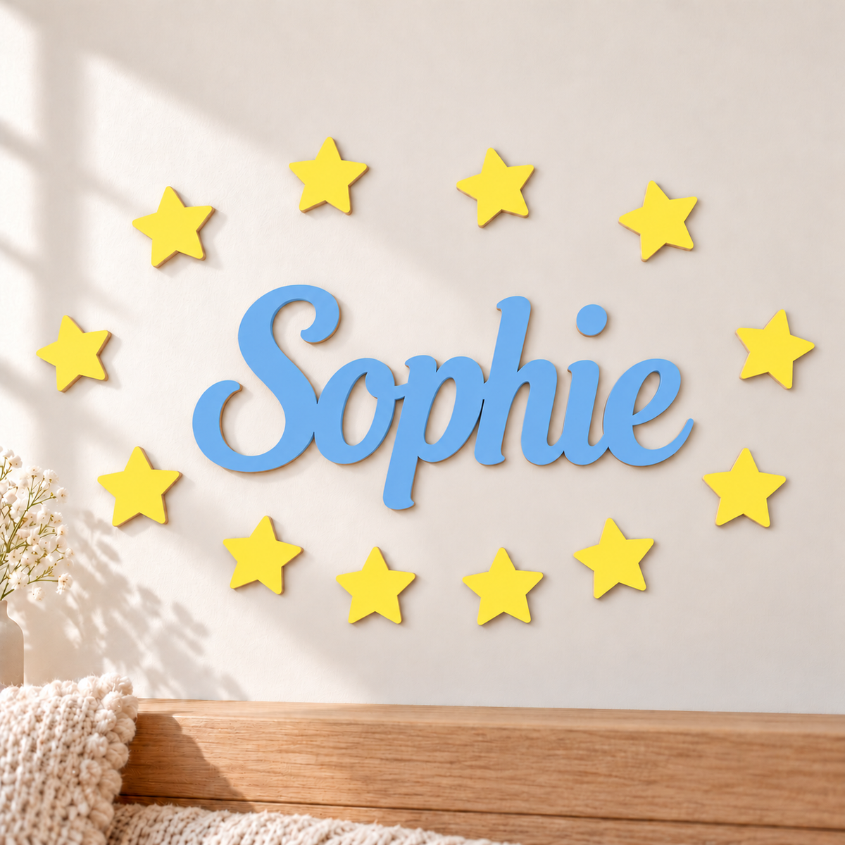 Light blue wooden name Sophie with twelve equal bright yellow stars in a neutral nursery