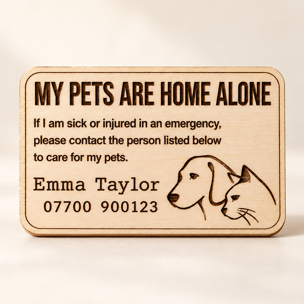 Wooden pet emergency contact card engraved with a sample contact name, phone number and dog and cat illustration.