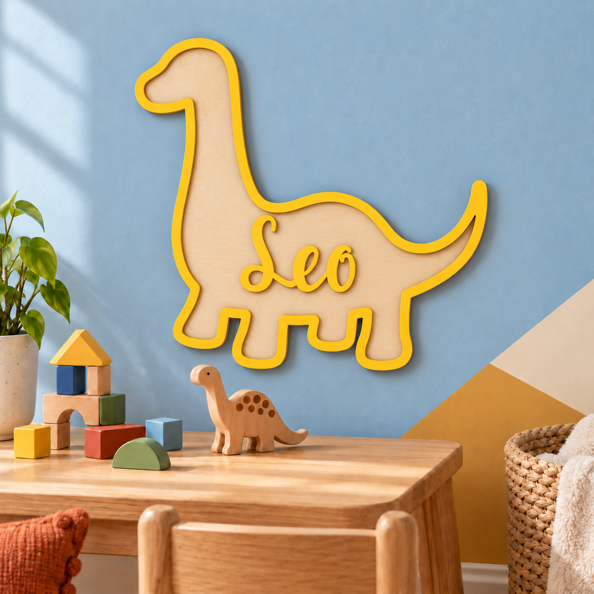 Yellow wooden brachiosaurus sign with the name Leo centred on its body, above a playroom table